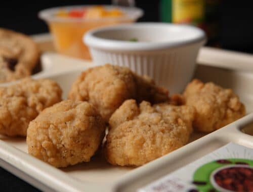Chicken nuggets on a tray with dipping sauce, cookie, and fruit cup