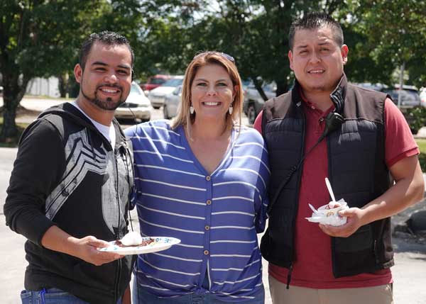 Two Men and a Woman smiling and holding food.